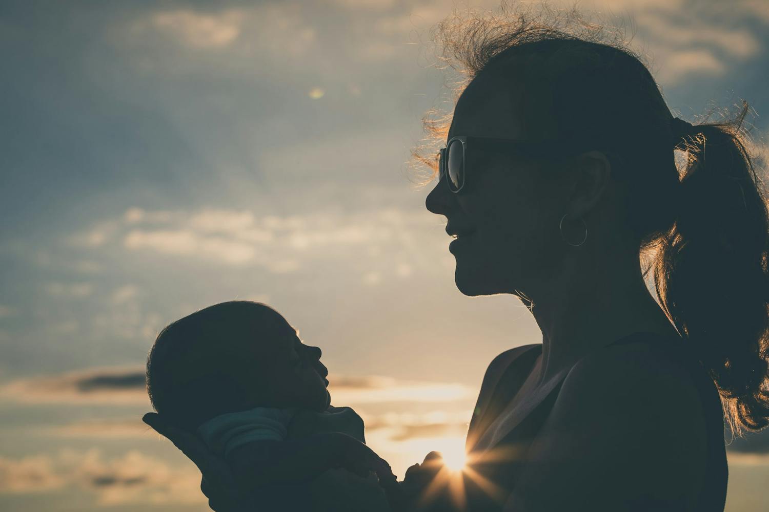 shutterstock 1198921681 5QoGFwbumHq0c Silhuett av mamma och barn i solnedgången.